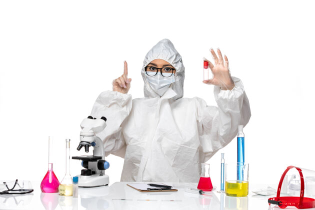 持有前视图穿着特殊防护服的女化学家拿着浅白色背景上的烧瓶病毒健康化学冠状病毒-人前面医生