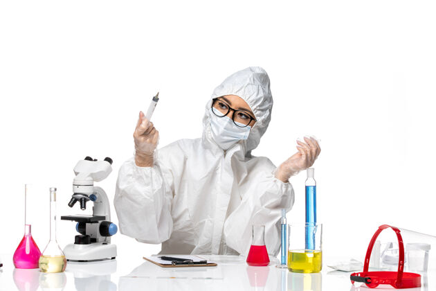 女化学家前视图穿着特殊防护服的女化学家手持注射在浅白色背景上化学冠状病毒大流行实验室外套保护药