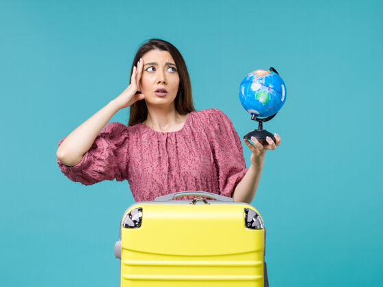 工艺前景度假中的女性手持蓝色背景上的小地球仪出海旅行女性度假暑假地球人假期