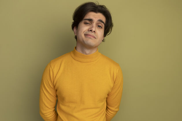 男人高兴的年轻帅哥穿着黄色高领毛衣隔离在橄榄绿的墙壁与复制空间毛衣姿势请
