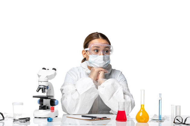 坐姿前视图穿着防护服戴着面罩的女医生正坐在白色背景的病毒药物上 预防健康大流行病毒医疗专业