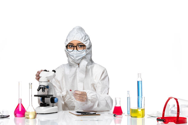 病毒前视图穿着特殊防护服的女化学家正在检查白色背景上的样本化学冠状病毒大流行女化学家健康大流行