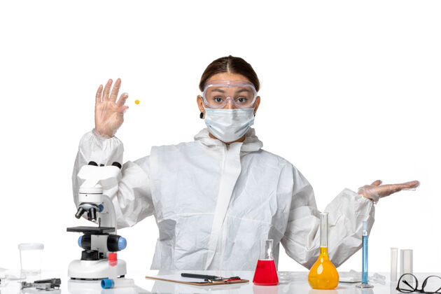 专业前视图：穿着防护服 戴着面罩的女医生 在浅白色背景上拿着样本 药物是柯维病毒-大流行病毒正面展示女医生