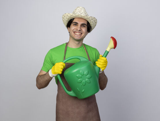 男人微笑着的年轻男园丁穿着制服戴着园艺帽拿着浇水罐帽子制服男人