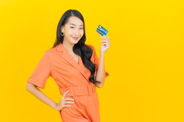 亚洲肖像美丽的亚洲年轻女子微笑信用卡上的黄色客户信用卡银行