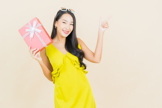 人肖像美丽的亚洲年轻女子微笑与红色礼品盒在彩色墙上女人礼品盒亚洲女人