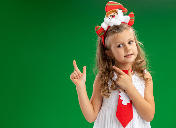 箍令人印象深刻的小女孩戴着圣诞发箍与领带点在后面孤立的绿色背景头发领带点