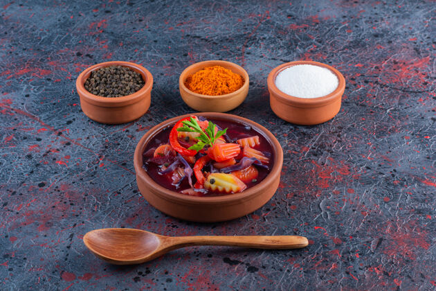 勺子一碗新鲜蔬菜汤和调味品放在大理石表面配料胡椒美味