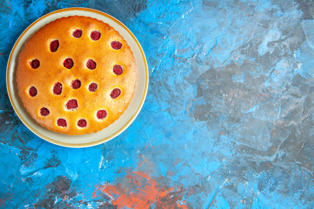 碗蓝色表面椭圆形盘子上草莓蛋糕的俯视图椭圆形特写液体