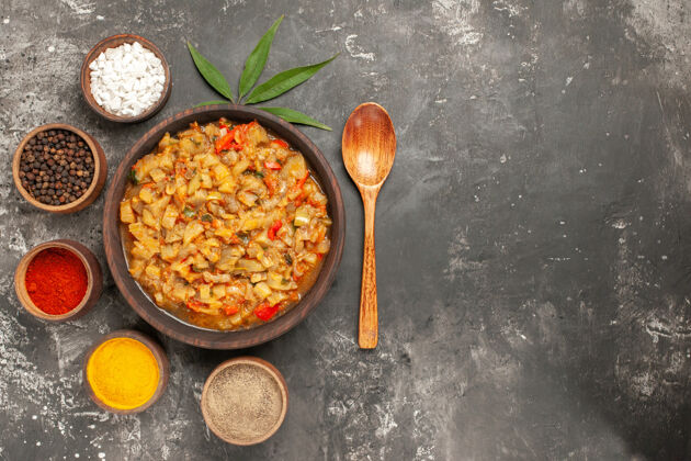 茄子沙拉顶视图烤茄子沙拉碗和不同香料碗勺叶在黑暗的表面烹饪农产品蔬菜