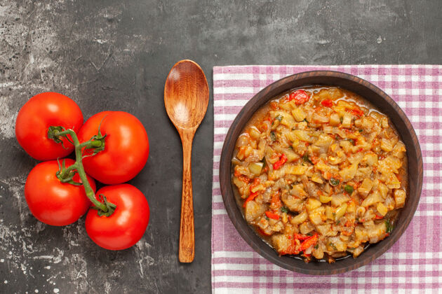 一餐顶视图烤茄子沙拉碗 木勺和西红柿在黑暗的表面蔬菜勺子黑