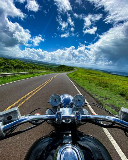 岩石垂直拍摄的一辆摩托车在公路上与夏威夷考艾岛美丽的山景速度自然路