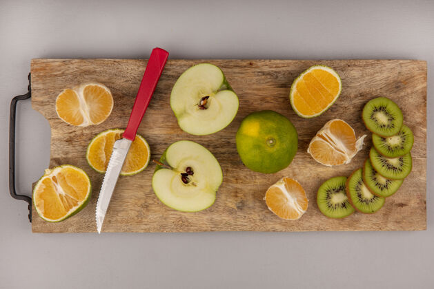 顶部美味的橘子切片与猕猴桃和苹果片在木制菜板与刀的俯视图木头食物灰色