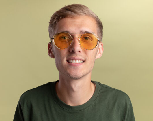 年轻微笑的年轻帅哥穿着绿色衬衫 眼镜孤立在橄榄绿的墙上眼镜帅哥橄榄
