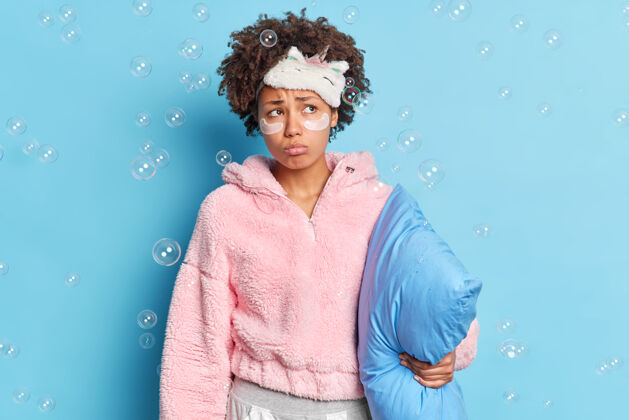 毯子在室内拍摄的体贴不幸的非裔美国妇女穿着睡衣抱着枕头一不满意枕头