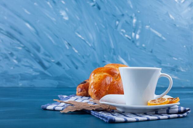 柠檬欧式早餐 新鲜牛角包 一杯茶和茶毛巾上的柠檬片茶碟叶子早餐