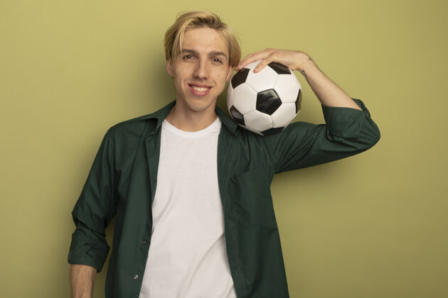 帅哥微笑的金发小伙子穿着绿色t恤 把球放在肩膀上年轻穿人