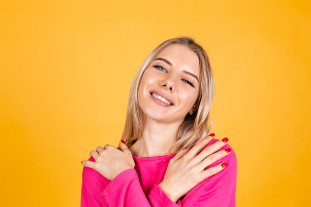 年轻黄色墙上穿粉红色上衣的漂亮欧洲女人积极健康时尚