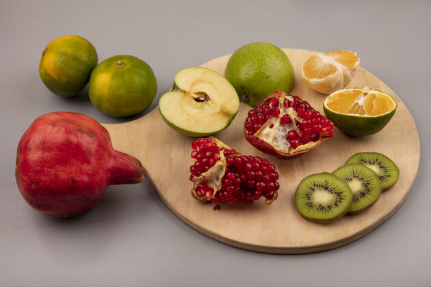 灰色健康的切片猕猴桃与苹果橘子和石榴在木制厨房板的俯视图健康木材切片