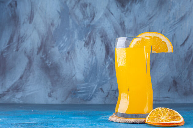 玻璃器皿一杯新鲜的橙汁放在彩色的背景上液体柑橘水果
