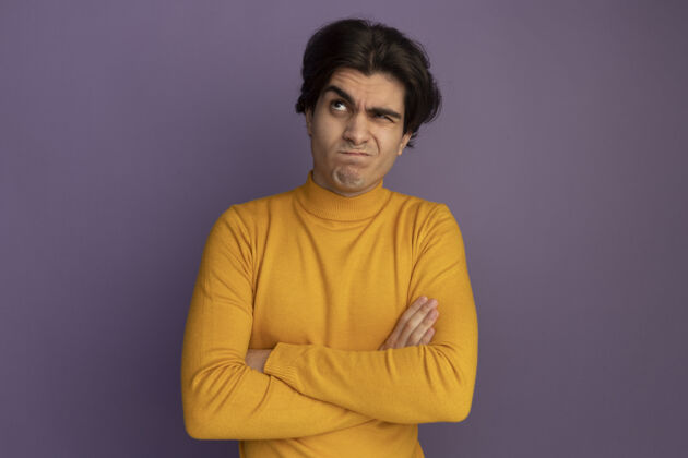 毛衣想着仰望着穿着黄色高领毛衣的年轻帅哥双手交叉隔离在紫色的墙上思考帅哥穿