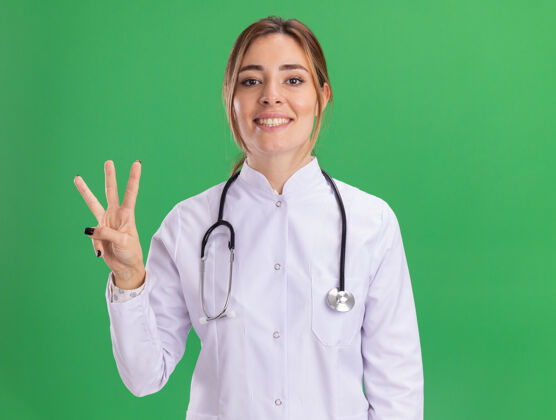 医生面带微笑的年轻女医生穿着医用长袍 听诊器显示绿色墙上有三个孤立的人长袍医疗穿