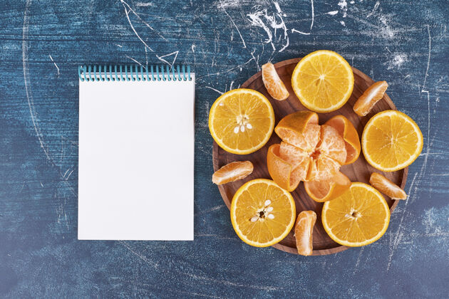 热带把橘子和柑桔片放在木盘子里 旁边放一个笔记本高质量的照片生物新鲜素食