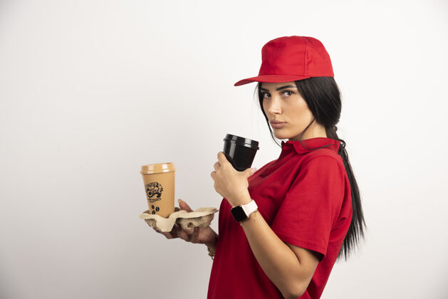 送货员严肃的信使摆出两杯咖啡在白色背景上高质量的照片女女孩肖像