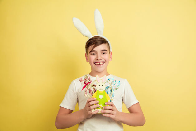 青少年快乐装饰白人男孩作为一个复活节兔子在黄色的工作室背景复活节快乐的问候美丽的男模人类情感的概念 面部表情 节日复制空间惊喜潮流人脸