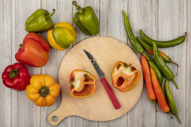 膳食顶视图橙色半甜椒在一个木制的厨房板与刀彩色辣椒隔离在灰色的木制背景自然胡椒蔬菜