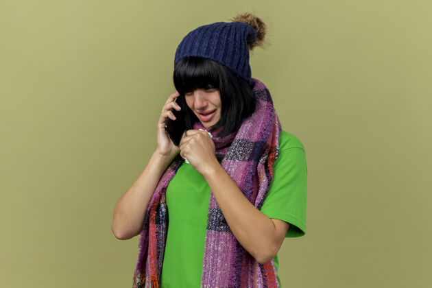 餐巾戴着冬日帽子 戴着围巾的年轻病妇在打电话 看着笔直地拿着餐巾咳嗽 隔离在橄榄绿的墙上 留着复印空间市民人表情