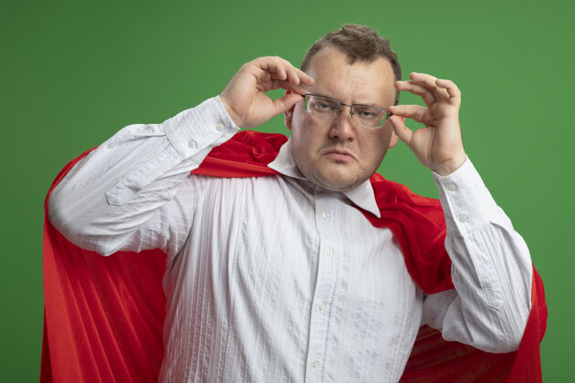 脸自信的成年斯拉夫超级英雄 穿着红斗篷 戴着眼镜 紧紧抓住他们 看着隔离在绿墙上的前方超级英雄姿势表情