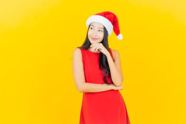 白色肖像美丽的亚洲年轻女子戴圣诞帽或发带在黄色的墙上年轻女士欢呼