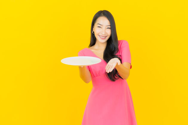 可爱画像美丽的亚洲年轻女子微笑着黄色墙上的空盘子盘子年轻喜悦