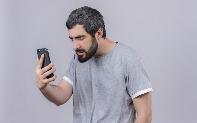 年轻一个年轻英俊的白人男子拿着手机 看着手机 手机被隔离在白色的背景上 还有复印空间帅气抱着手机