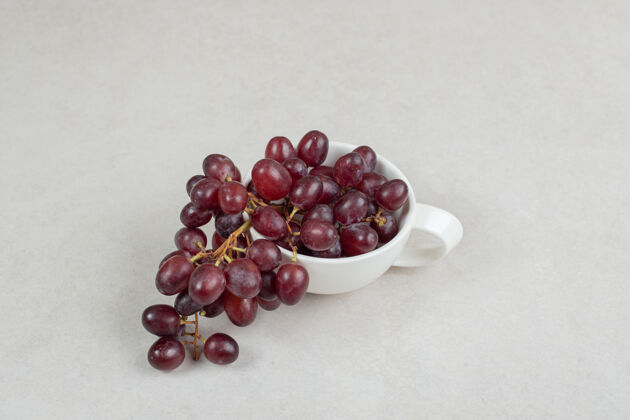 天然白杯中的新鲜红葡萄成熟新鲜簇状