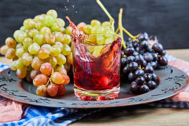 葡萄一束葡萄和一杯果汁在深色背景上高质量的照片收获餐桌盘子