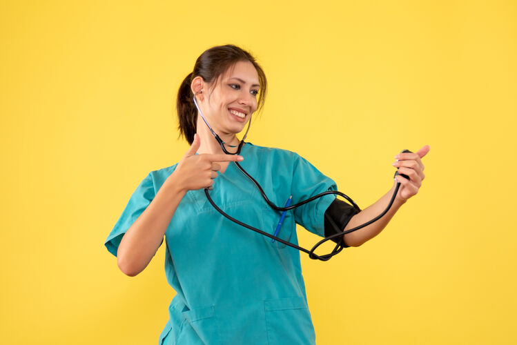 健康前视图穿着医用衬衫的女医生正在检查黄色背景上的压力前面压力视图