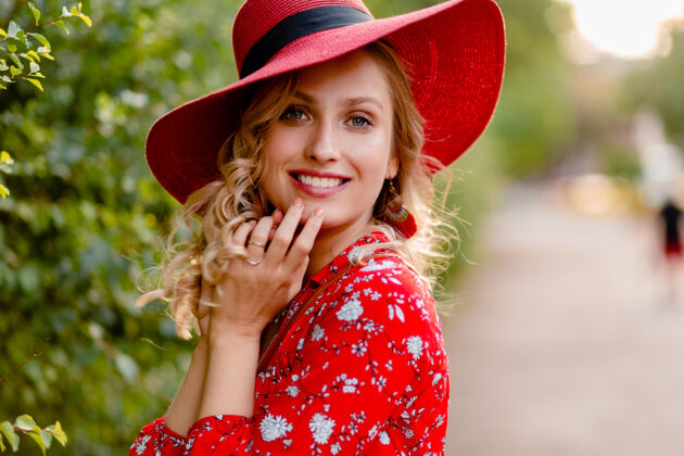 白色近距离肖像迷人的时尚金发微笑的妇女在稻草红色帽子和衬衫夏季时尚套装与微笑卷曲的发型魅力帽子明亮