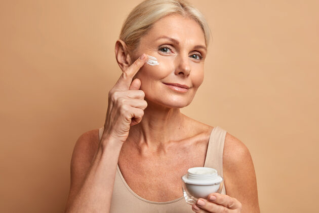 外观中年美女在脸上应用抗衰老霜进行美容护理皮肤成熟老年美丽