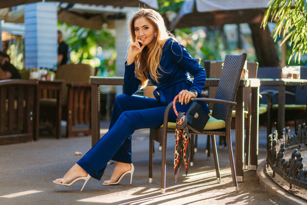 城市阳光明媚的日子里 一位身着优雅蓝色套装的微笑美女坐在咖啡馆里优雅街头女士