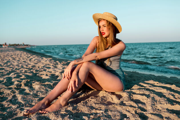 热带美丽的金发女人戴着草帽在海边散步的户外夏日形象自然全长海洋