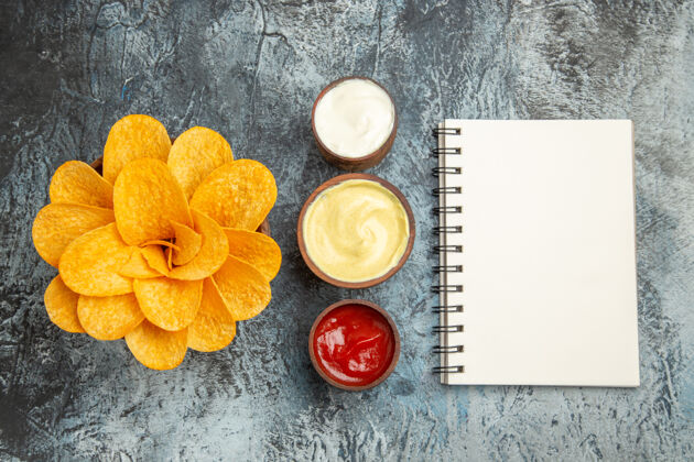 笔记本俯瞰图自制薯片装饰像花形和盐与番茄酱蛋黄酱和笔记本在灰色的桌子上番茄酱蛋黄酱形状