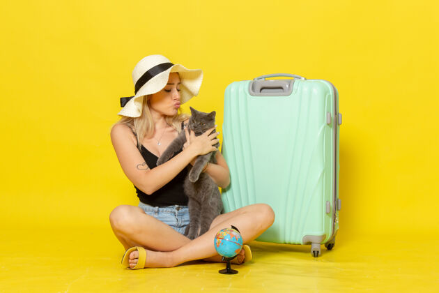 风景正面图年轻的女性坐在她的绿色袋子抱着小猫在黄墙上旅行度假海上旅行太阳年轻人海猫