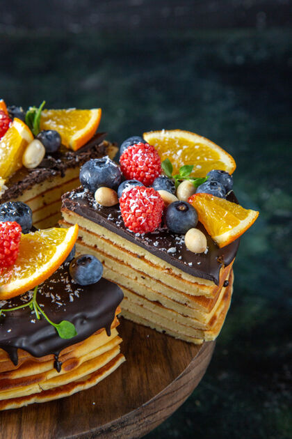 新鲜的正面是美味的巧克力蛋糕 黑墙上有水果派蓝莓糖