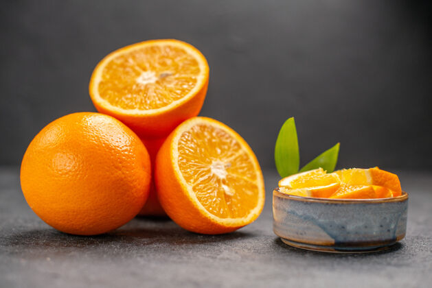 水果在黑暗的桌子上近距离观看整个和切碎的新鲜橙子柑橘饮食橙子
