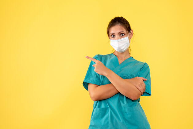 女医生前视图黄色背景上穿着医用衬衫和面罩的女医生流行病视图黄色