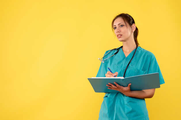 职业前视图穿着医用衬衫的女医生在黄色背景上写笔记医疗病毒衬衫