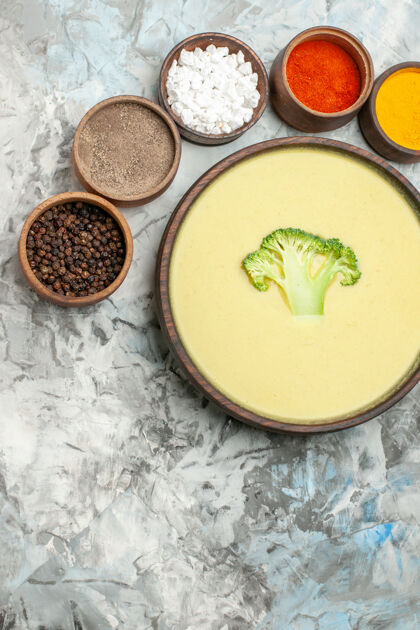 晚餐奶油西兰花汤在一个棕色的碗和不同的调味品对灰色表股票图像蔬菜碗汤碗