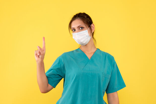 护士前视图黄色背景上穿着医用衬衫和面罩的女医生病毒医疗外套